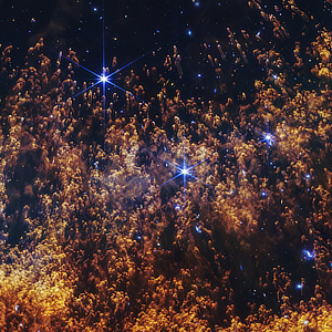 A near-infrared image of a section of the Helix Nebula in Aquarius (NGC 7293) by the James Webb Space Telescope showing the bright columnar structures formed where the solar winds from the dying star meet the surrounding cold gas and dust.
