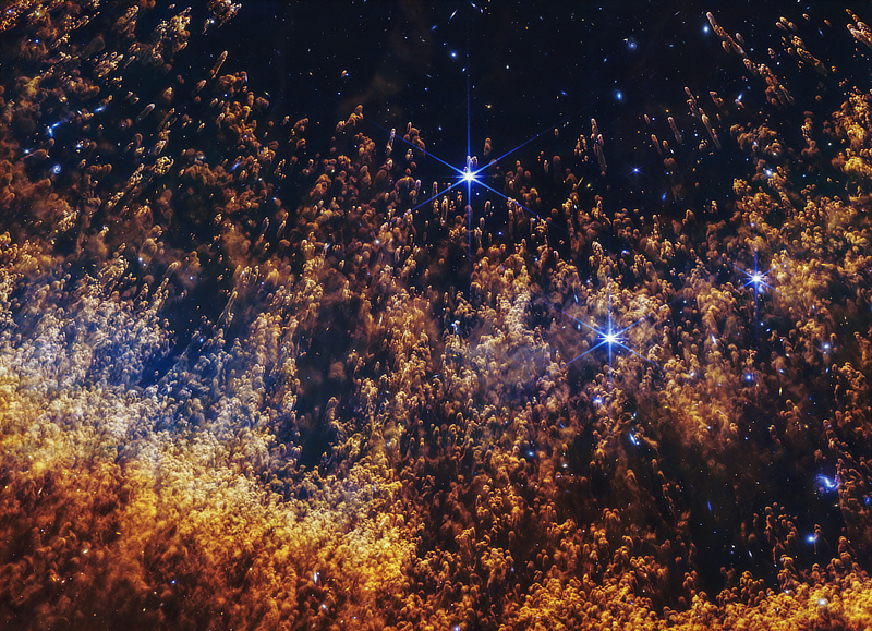 A near-infrared image of a section of the Helix Nebula in Aquarius (NGC 7293) by the James Webb Space Telescope showing the bright columnar structures formed where the solar winds from the dying star meet the surrounding cold gas and dust.